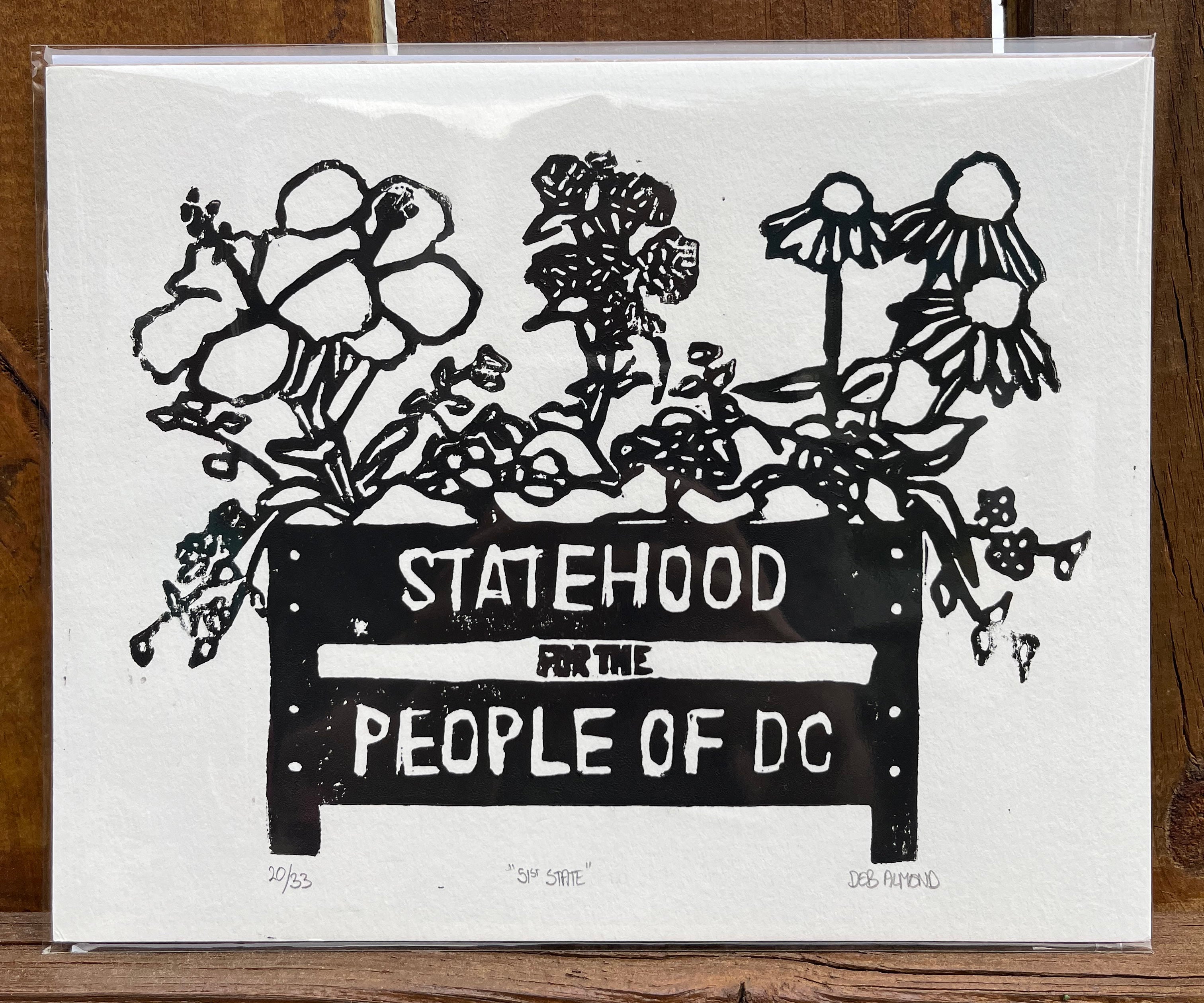 Hand printed block print based on the DC flag and a flower bed that reads 'Statehood For The People Of DC'.